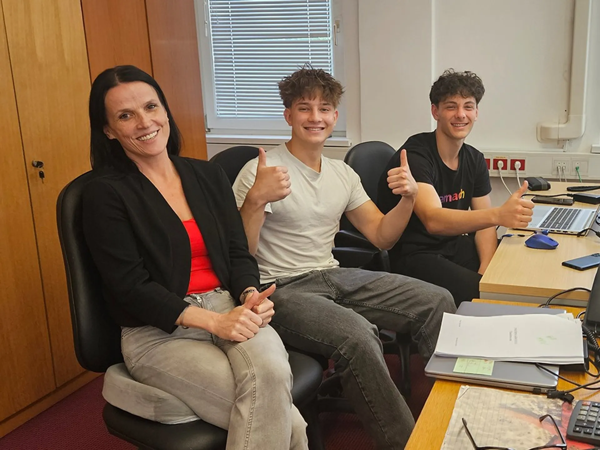 Ekipa mentorjev in študentov na praksi pri projektu, ki sodelujejo in razpravljajo v pisarni.